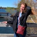 Lauren Schilling leaning against a railing by a lake