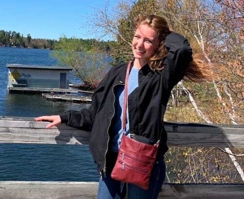 Lauren Schilling leaning against a railing by a lake