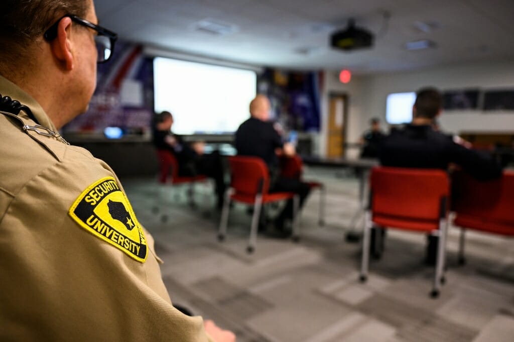 A group of police officers gather around a room.