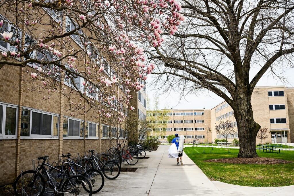 A man carries a carpet and more from a student's room in Cole Residence Hall.