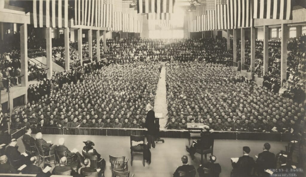 Charles Van Hise standing at podium before an audience of hundreds seated on the floor of the Stock Pavilion