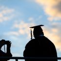 Seen in silhouette against a sunset sky, a family member makes one last photo of their graduate outside the Kohl Center at the University of Wisconsin-Madison following UW-Madison's spring commencement ceremony on May 10, 2019. The indoor graduation was attended by more than 900 doctoral, MFA and medical professional degree candidates. (Photo by Jeff Miller / UW-Madison)