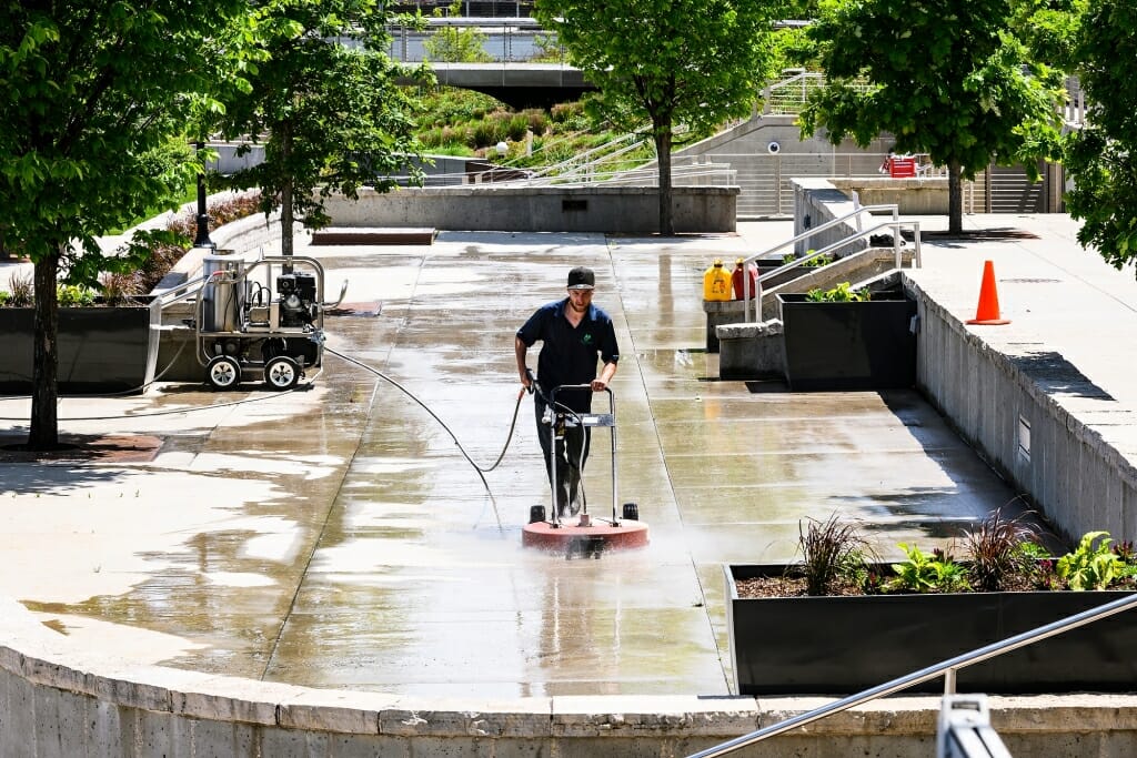 A lone worker scrubs an empty Terrace with a power-washing machine.