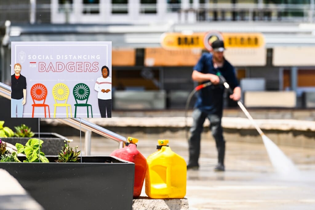 A lone worker scrubs the terrace in front of the Brat Stand, with ketchup and mustard visible.