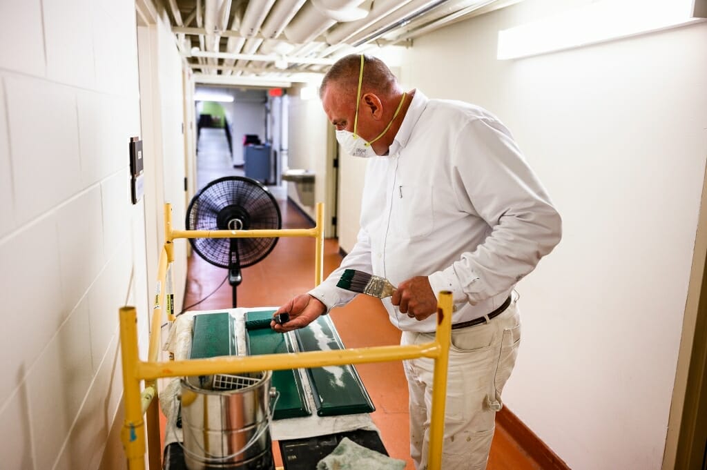 A man paints metal fixtures.