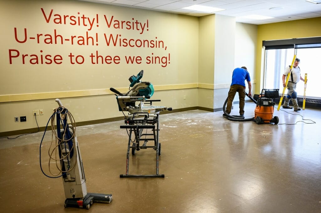 Two employees clean up tools in an emptyh conference room.