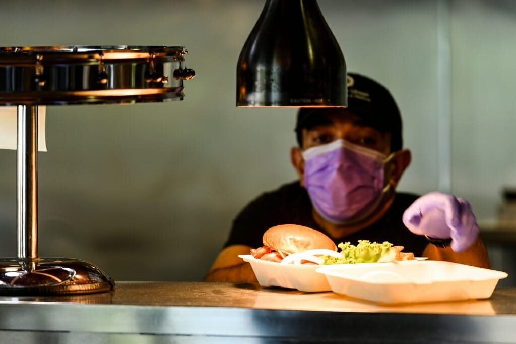 A cook puts food under warming lamps.