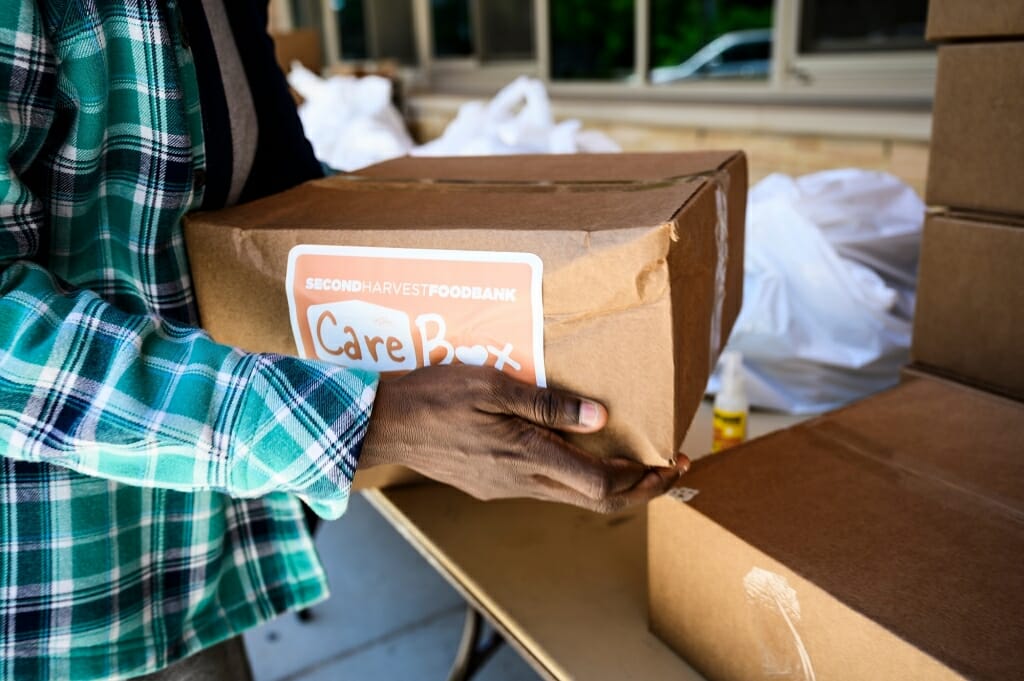 A woman's hands hold up a cardboard container of food.