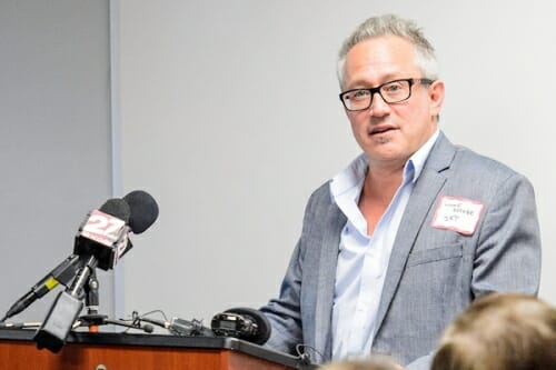 Lonnie Berger speaking into a microphone at a podium