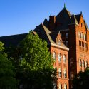 A picture of the red stone Science Hall building, sunshine lighting up its front.