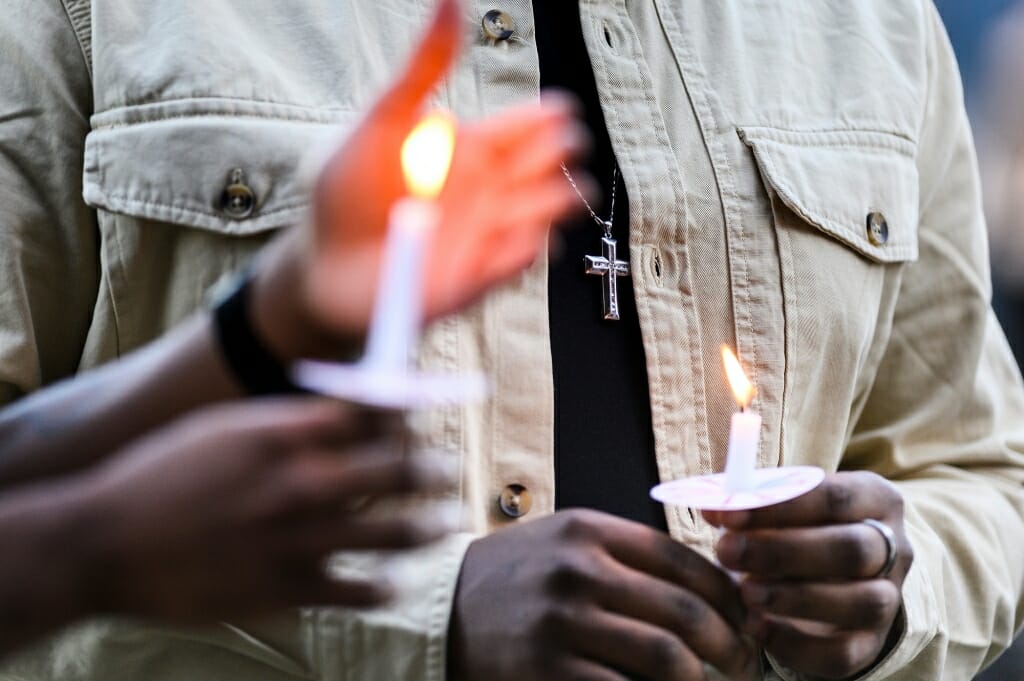 Hands hold lit candles.