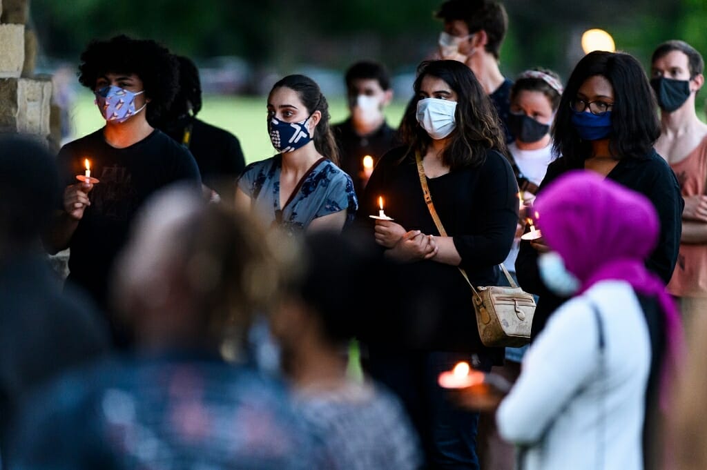 People gather holding lit candles.