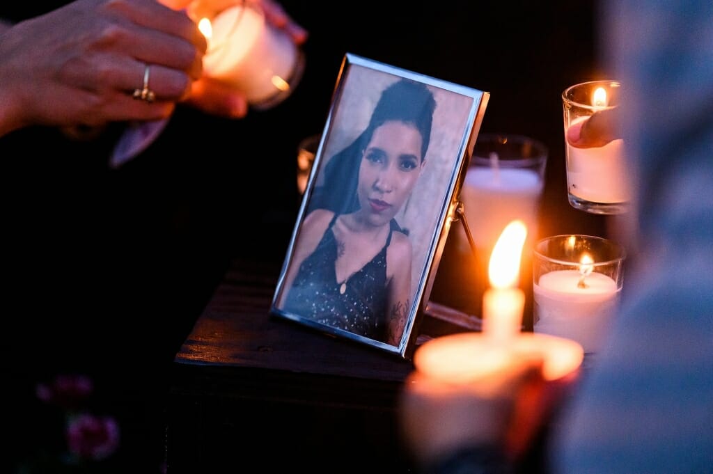 A candle is held next to a framed photo of Bella Sobah.