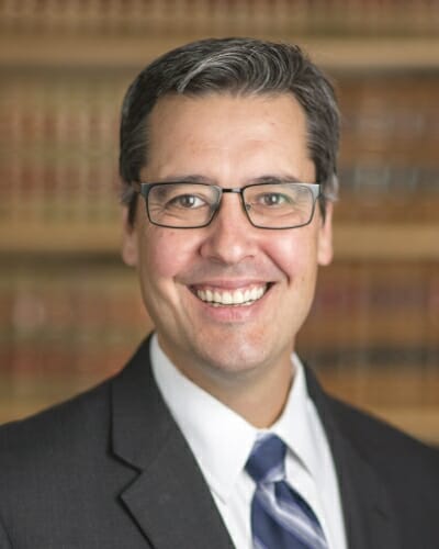 Portrait of Daniel Tokaji in front of a shelf full of law books