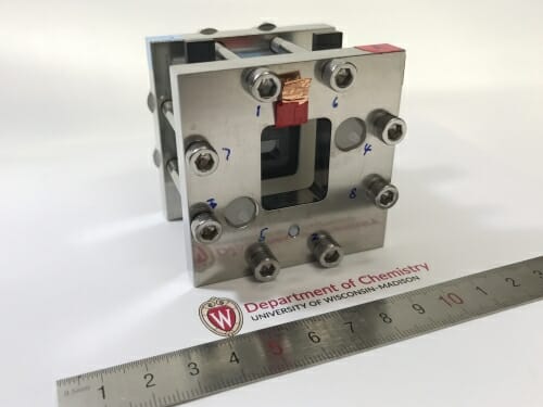 Solar flow battery resting on a table next to a ruler measuring 6 inches across