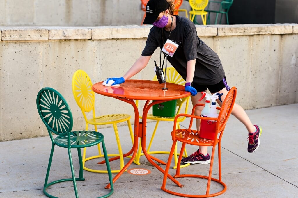 A person cleans off an orange Terrace table.