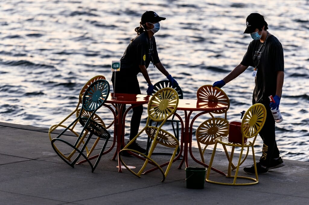 Workers clear off a table as the lake water is visible in the background.