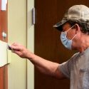 Painter wearing mask brushing paint on wall