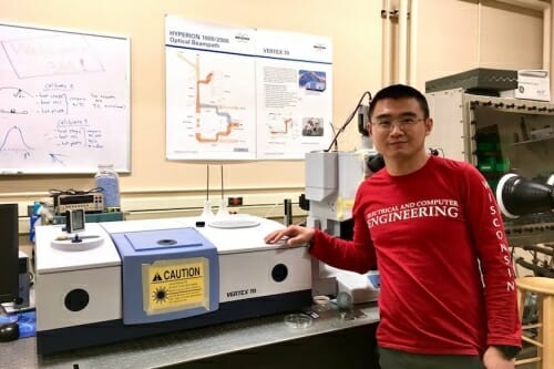 Yuzhe Xiao standing in front of a spectrometer