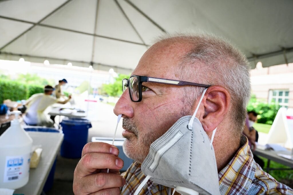 After receiving instruction from University Health Services staff, Jeff Miller, senior photographer in University Communications, self-administers a nasal-swab test at a COVID-19 testing tent.