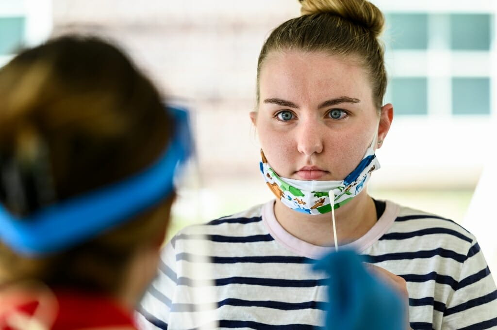 A student listens to a University Health Services staff member’s instruction for self-administering a nasal-swab test.