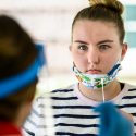 A student listens to a University Health Services staff member’s instruction for self-administering a nasal-swab test.