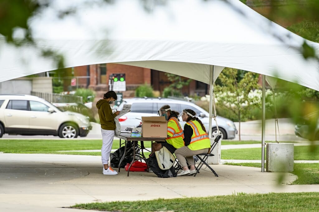 Poll workers wearing personal protective equipment help voters during an early in-person absentee voting session held on Library Mall.