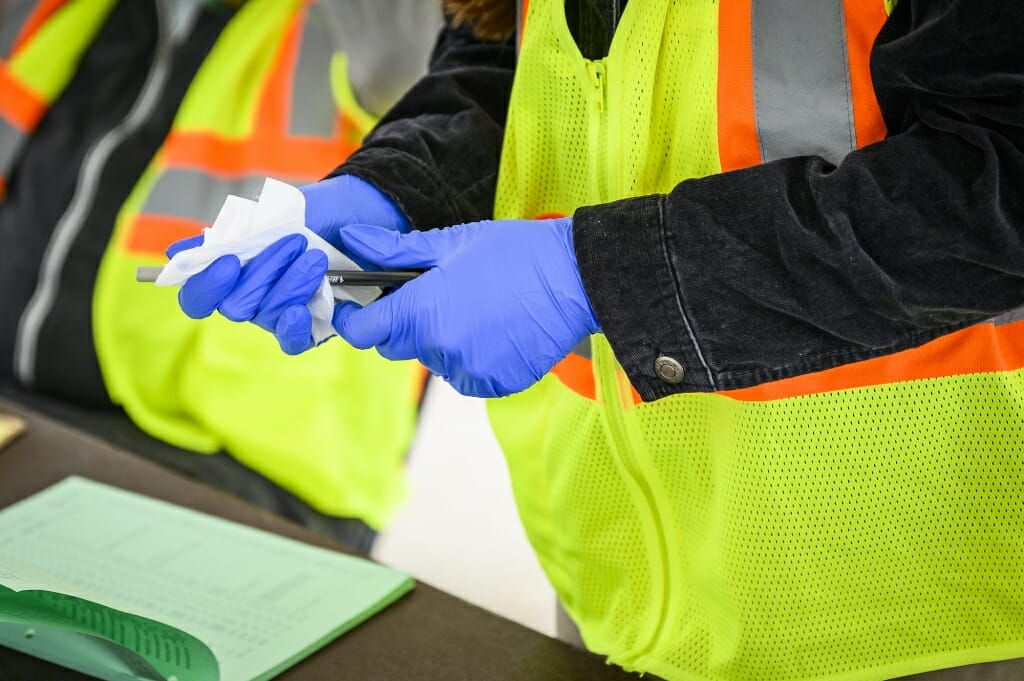 Disinfectant is used to clean off a pen and clipboard between voters.