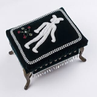 A black and white footstool with a stylized image of a man upon it.