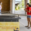 Wearing face masks and maintaining physical distance from others during the global coronavirus (COVID-19) pandemic, undergraduate students Tess Riley (left) and Xi (Chelsea) Chen (right) talk outside of the Engineering Building at the University of Wisconsin-Madison on Aug. 7, 2020. The photo was made as part of a UW-Madison Smart Restart marketing campaign and demonstrates health and safety protocols as campus reopens for the Fall 2020 semester. (Photo by Bryce Richter / UW-Madison)