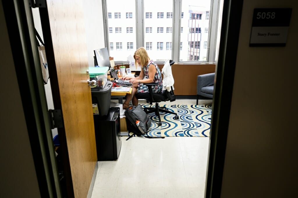 Exempt from wearing a face mask while working alone in her closed office in Vilas Hall, Stacy Forster Benedict, a faculty associate in the Department of Journalism and Mass Communication, leads an online virtual session with students from her Curb magazine production class.