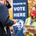 Ann Elise Trafford, with the City of Madison Clerk’s Office, right, helps students register to vote.