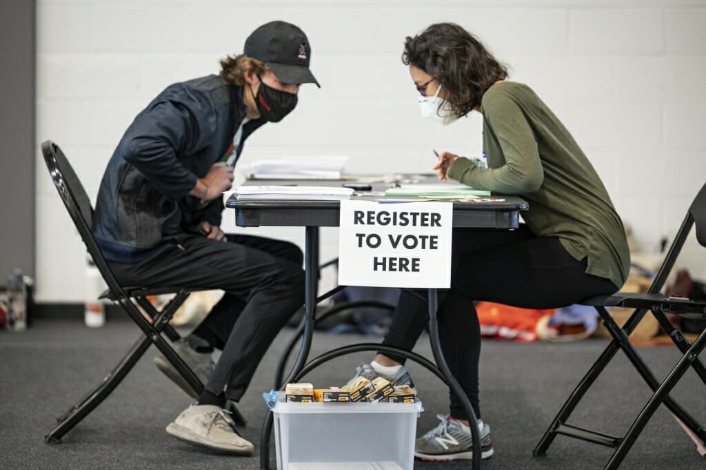 A poll worker helps a student register to vote at the Nicholas Recreation Center polling station.