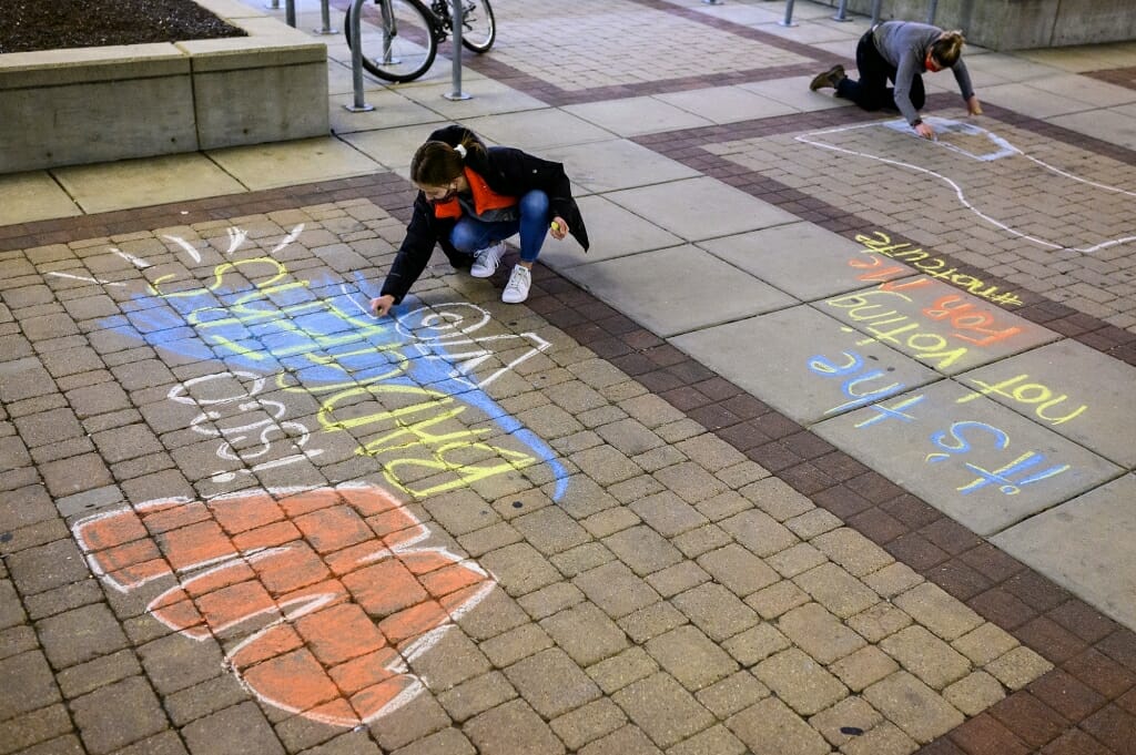 On Nov. 2, students Ellen Abad Santos (left) and Angela Maloney work with others in the #BadgersVote coalition to chalk messages on East Campus Mall.