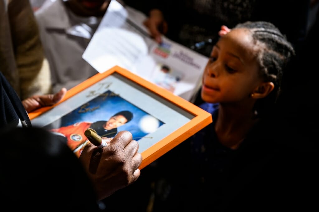 Closeup of hand signing picture while child watches