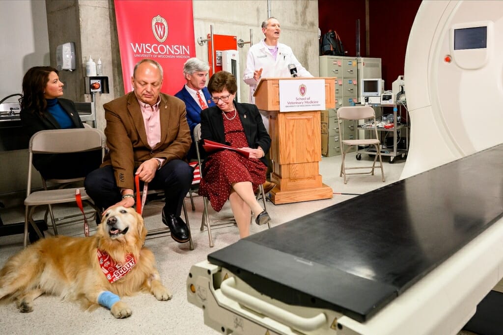 People and a dog sitting next to a tomography machine