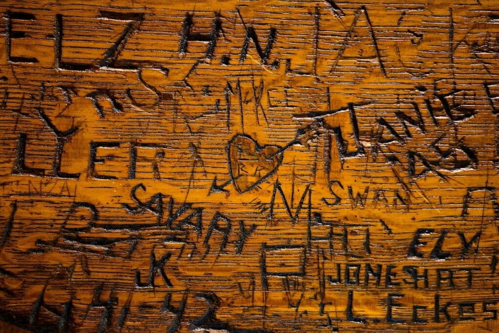 Closeup of tabletop with names carved into wood