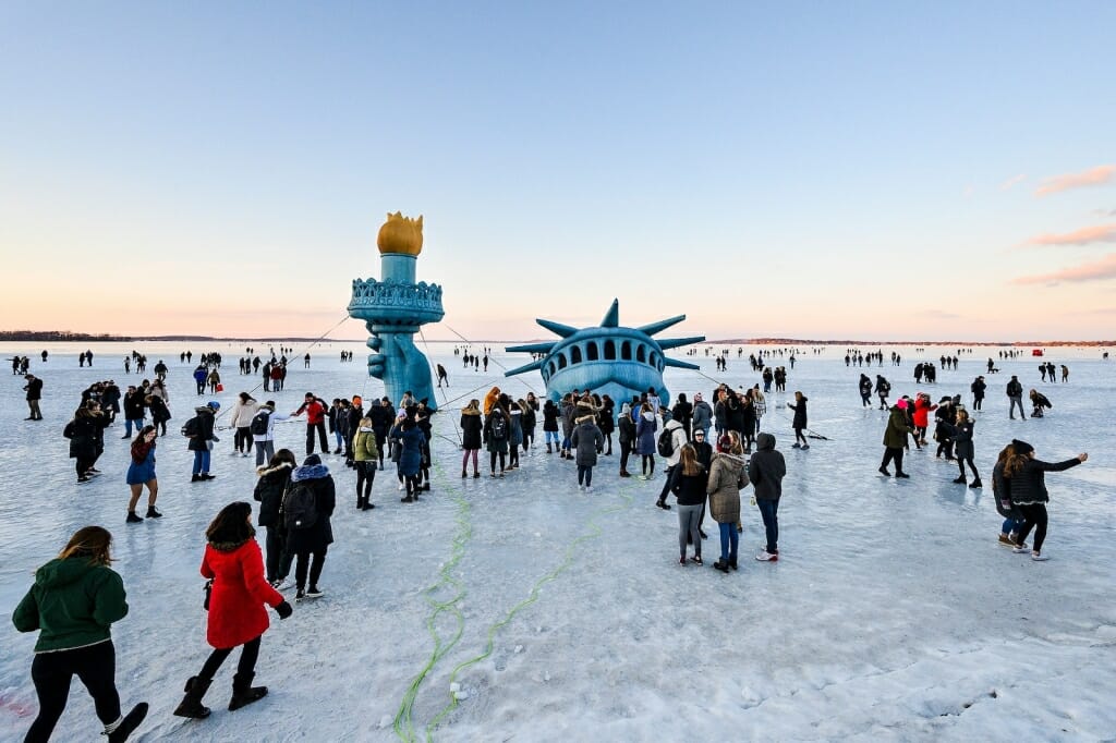 People gathering around Statue of Liberty display on frozen lake