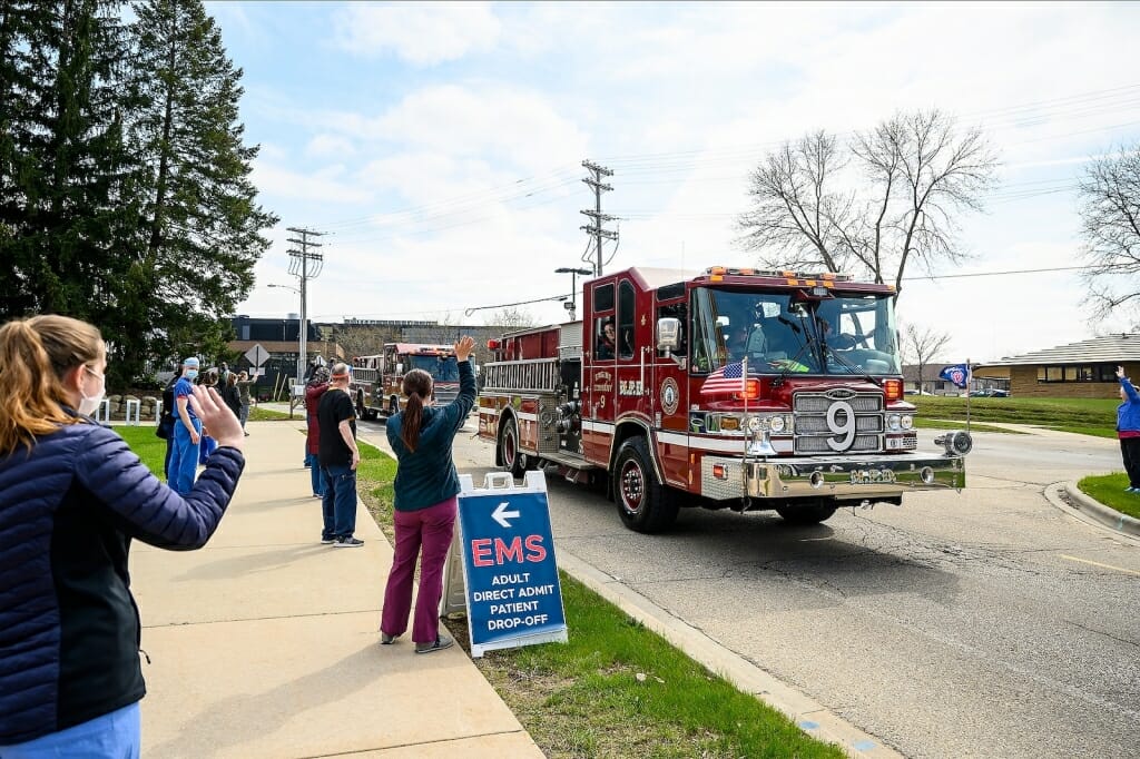 Firetruck driving past people on sidewalk