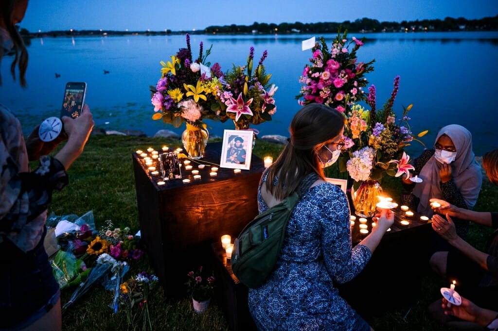 People looking at pictures by candlelight next to lake