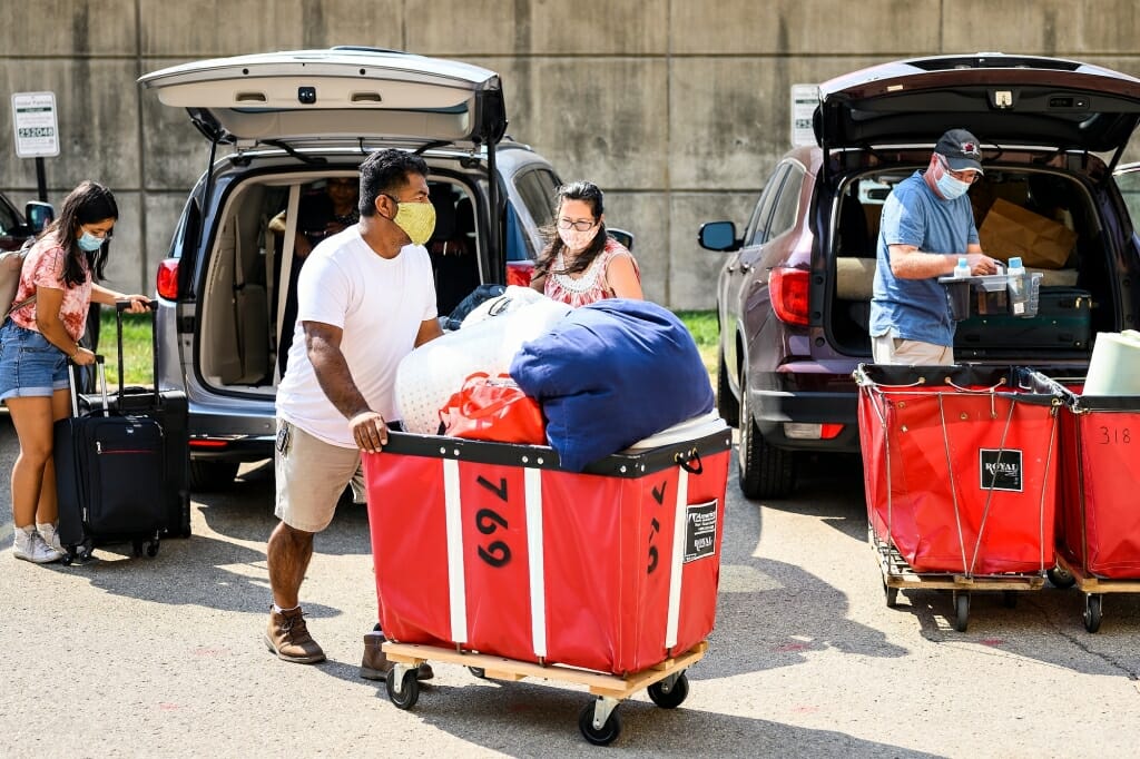 Person pushing laundry cart filled with belongings