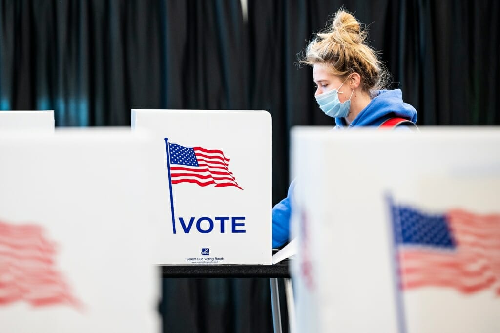 Person in face covering voting in a polling booth