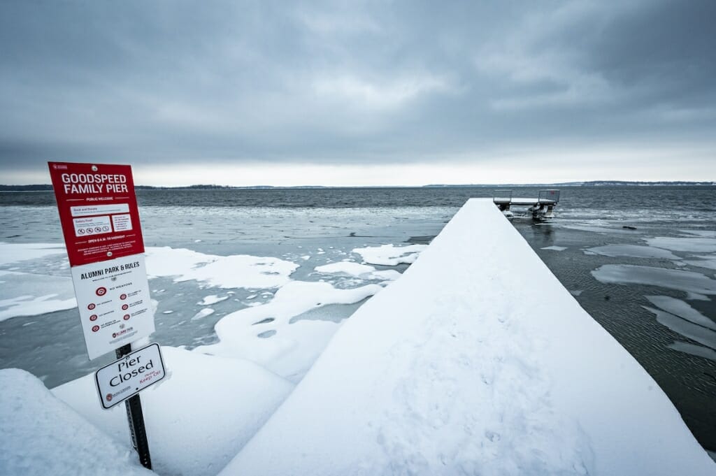 Sign that says Pier Closed next to snow-covered pier