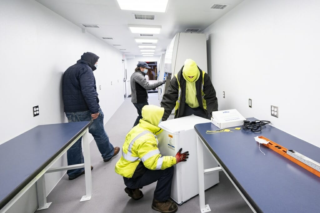 Workers install lab freezers in the mobile testing lab.