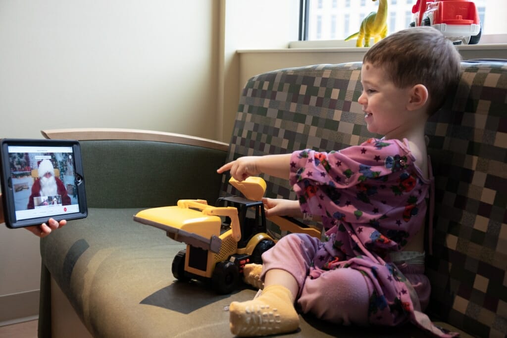 Landen Montes, 2, of Metamora, Mich., shows his truck to Santa Claus during the video visit.