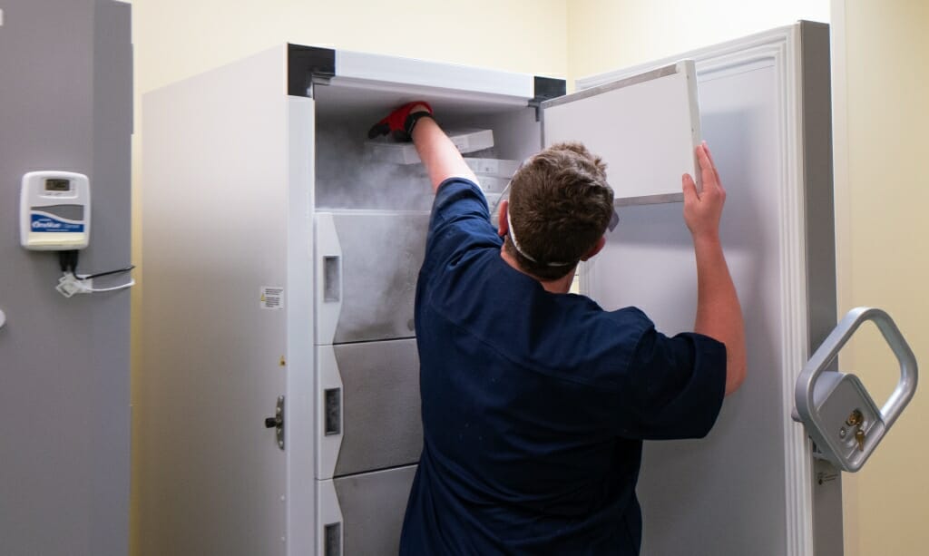 Gardner stores the tray of vaccines in a freezer at UW Health. The vaccine must be stored at minus 70 degrees Celsius.