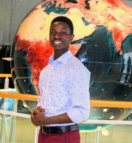 Joel Baraka standing in front of a large globe turned to Africa