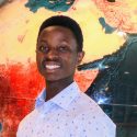 Joel Baraka standing in front of a large globe turned to Africa