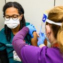 Nurse Nicole Metko, right, vaccinates Eden Charles, a researcher in the School of Medicine and Public Health Department of Emergency Medicine, with the first of a two-dose shot of the Moderna COVID-19 vaccine as eligible Phase 1a recipients begin receiving coronavirus vaccinations at University Health Services at the University of Wisconsin-Madison on Jan. 5, 2021. This initial phase of vaccination for members of the UW-Madison community includes frontline health care workers and others in direct contact with COVID-19 patients, or in direct contact with the virus that causes COVID-19 or virus specimens. (Photo by Jeff Miller / UW-Madison)