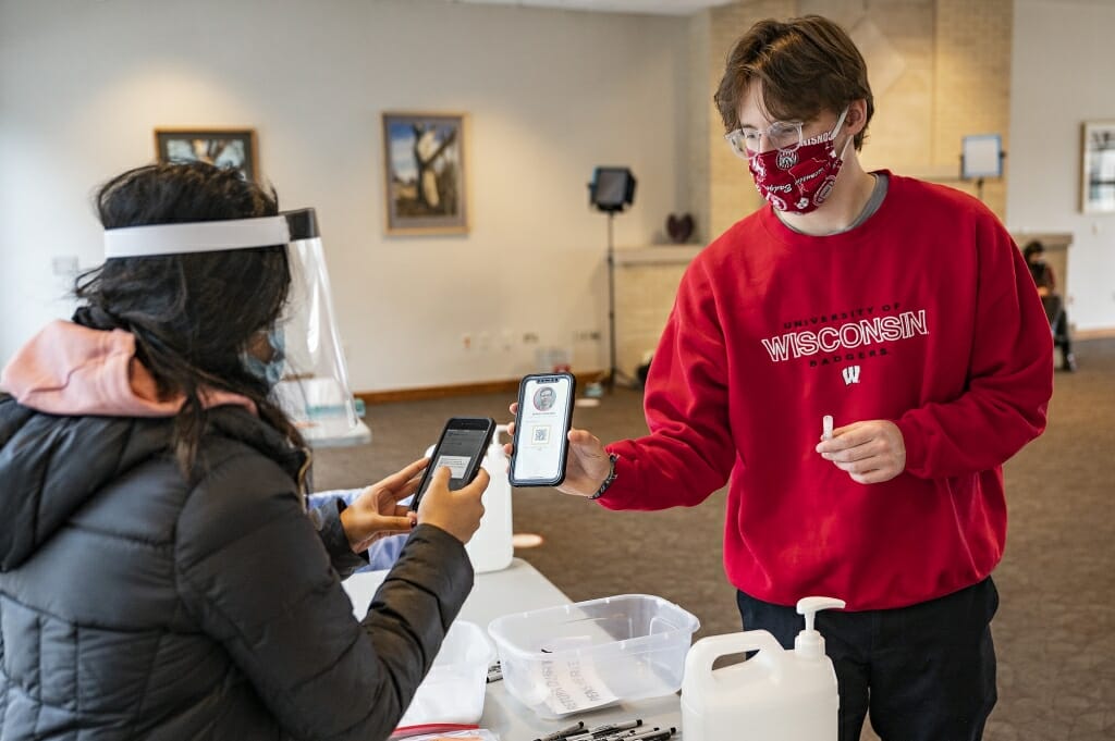 Student Sam Kavajecz uses the Safer Badgers phone app when submitting the saliva test. The app QR code is scanned in.